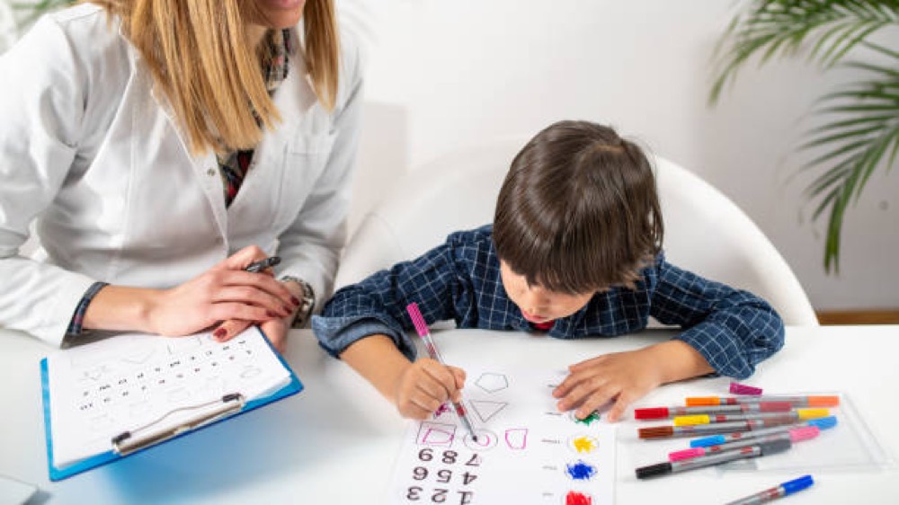An assessor working through shape and number tasks with a young child