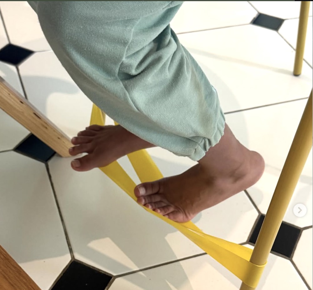 A child using a resistance band on a chair to help with movement and focus